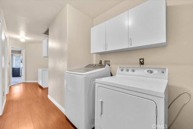 laundry room featuring visible vents, baseboards, cabinet space, light wood-style floors, and washer and dryer