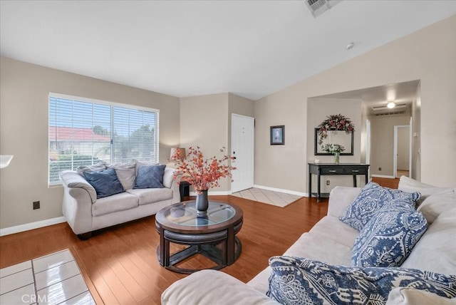 living area featuring lofted ceiling, wood finished floors, visible vents, and baseboards