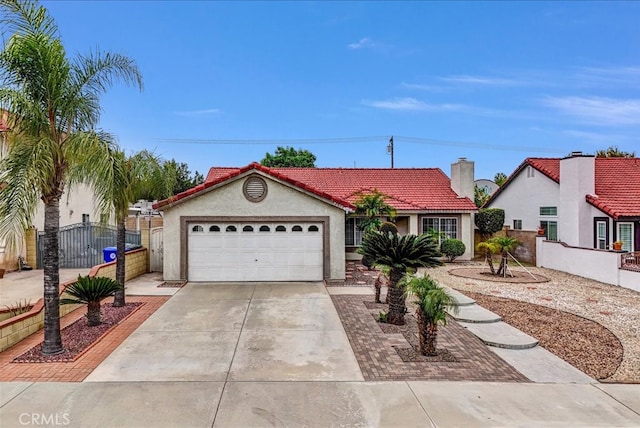 mediterranean / spanish home with stucco siding, a gate, concrete driveway, an attached garage, and a tiled roof