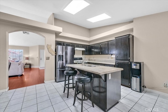 kitchen featuring light tile patterned floors, stainless steel fridge with ice dispenser, arched walkways, and freestanding refrigerator