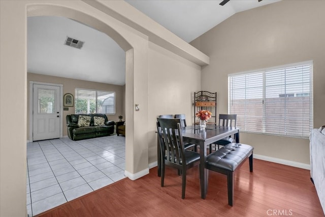 dining room with visible vents, arched walkways, wood finished floors, and vaulted ceiling