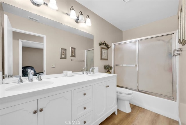 full bathroom featuring double vanity, visible vents, wood finished floors, and a sink