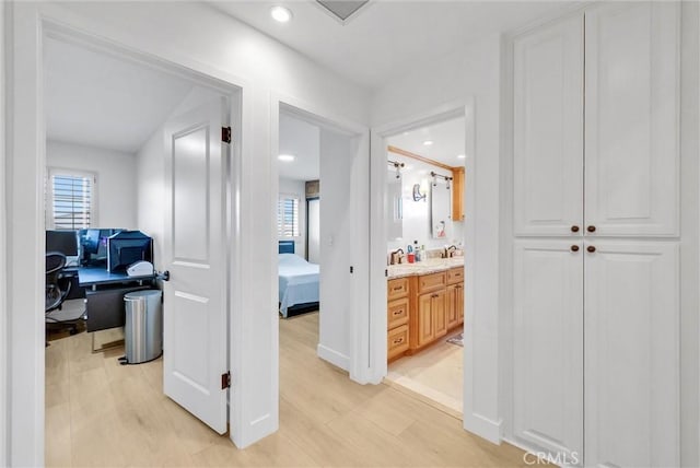 hall with recessed lighting, light wood-type flooring, and a sink