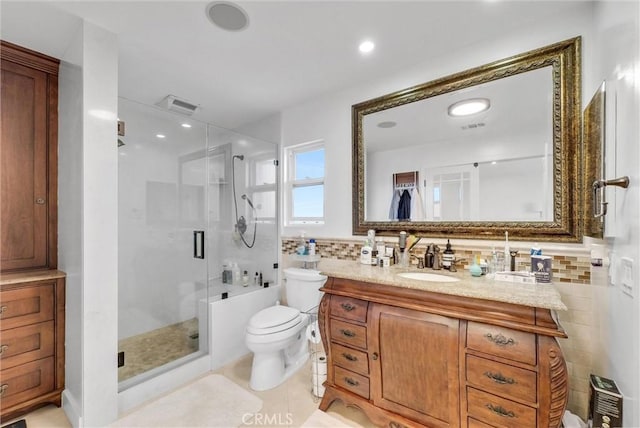 full bath with visible vents, a shower stall, tile walls, toilet, and vanity