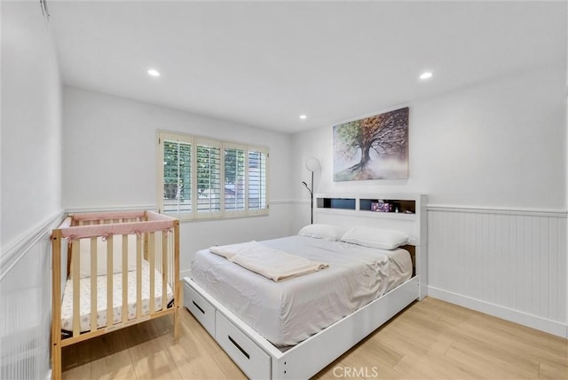 bedroom with recessed lighting, wood finished floors, and wainscoting