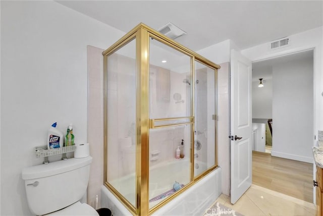 bathroom featuring visible vents, shower / bath combination with glass door, vanity, and toilet