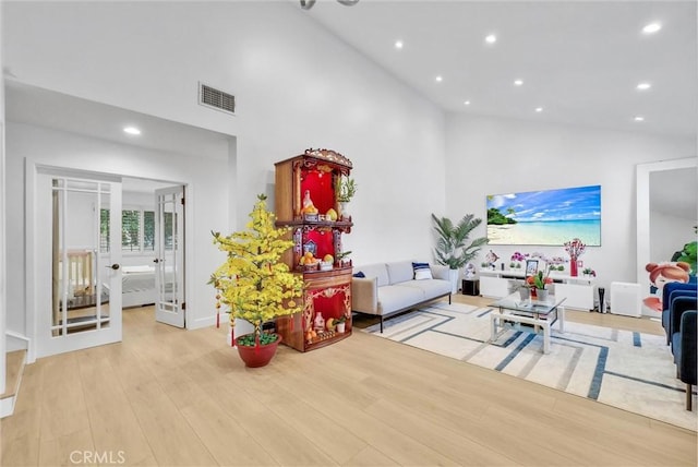 living room with french doors, high vaulted ceiling, visible vents, and wood finished floors