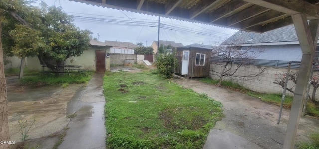 view of yard with an outdoor structure, a storage unit, and fence