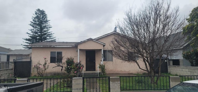 view of front facade with stucco siding, a fenced front yard, and a gate