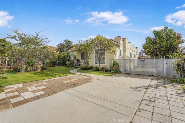 view of front facade with stucco siding, fence, a front yard, and a gate