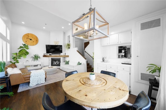 dining space featuring a glass covered fireplace, stairway, recessed lighting, and wood finished floors