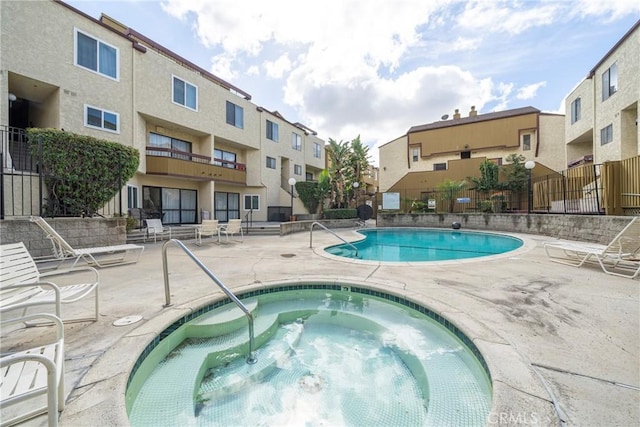 pool with a hot tub, a patio, and fence