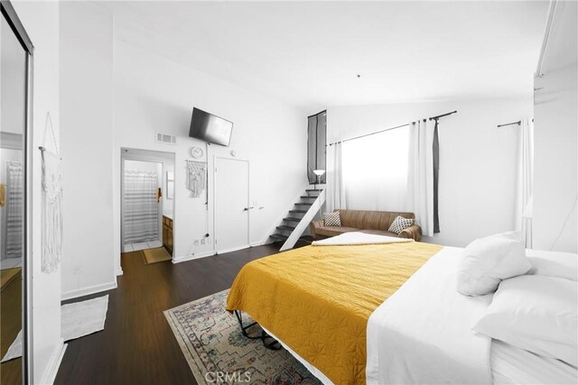 bedroom with visible vents, baseboards, wood finished floors, and vaulted ceiling