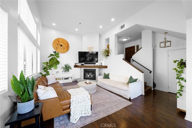 living room featuring visible vents, a glass covered fireplace, wood finished floors, recessed lighting, and stairway