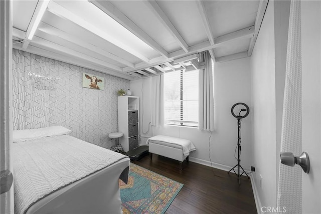 bedroom with beamed ceiling, baseboards, and wood finished floors