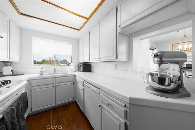 kitchen featuring dark wood finished floors, white cabinets, white dishwasher, and a sink