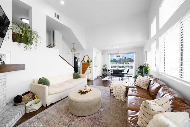 living area featuring dark wood finished floors, recessed lighting, visible vents, and a towering ceiling