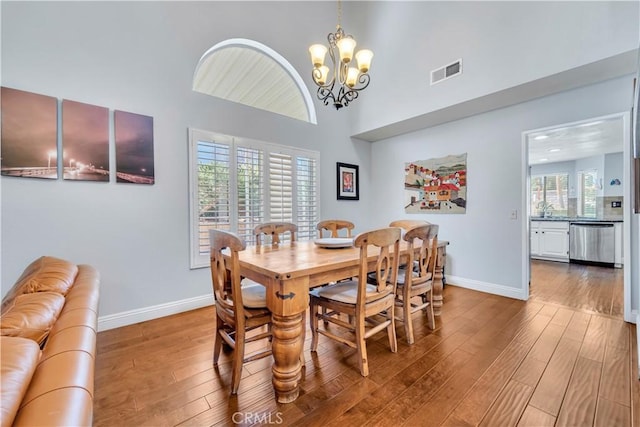 dining space with visible vents, baseboards, high vaulted ceiling, and hardwood / wood-style flooring