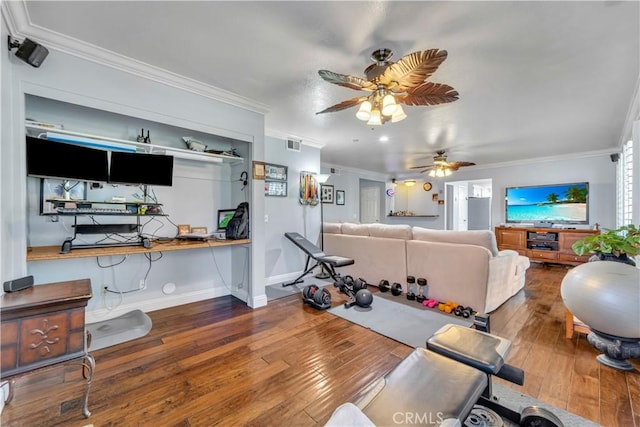 workout room with baseboards, visible vents, wood-type flooring, and ornamental molding