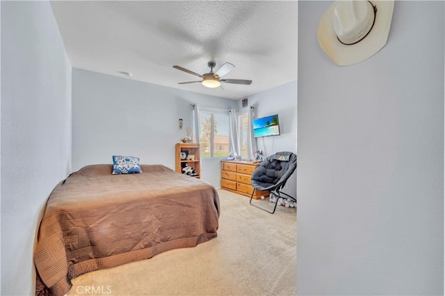 bedroom featuring light carpet, a textured ceiling, and a ceiling fan