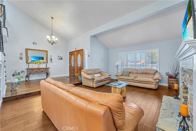 living area featuring visible vents, baseboards, a chandelier, a stone fireplace, and wood-type flooring