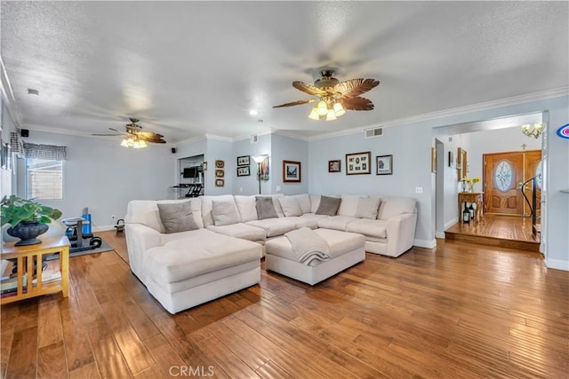 living room featuring baseboards, light wood-style floors, ornamental molding, and a textured ceiling