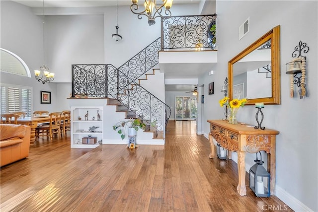 foyer entrance with stairway, a towering ceiling, baseboards, and wood finished floors