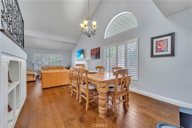 dining space featuring a fireplace, a healthy amount of sunlight, wood-type flooring, and a chandelier