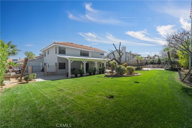 rear view of house featuring a yard, a patio area, stucco siding, and fence