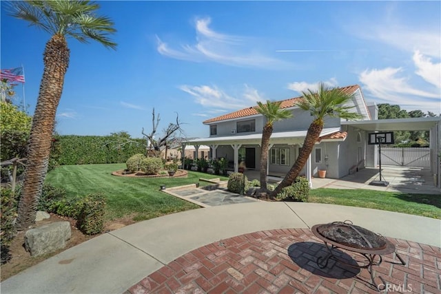 mediterranean / spanish house with stucco siding, a gate, a fire pit, a front yard, and a tiled roof