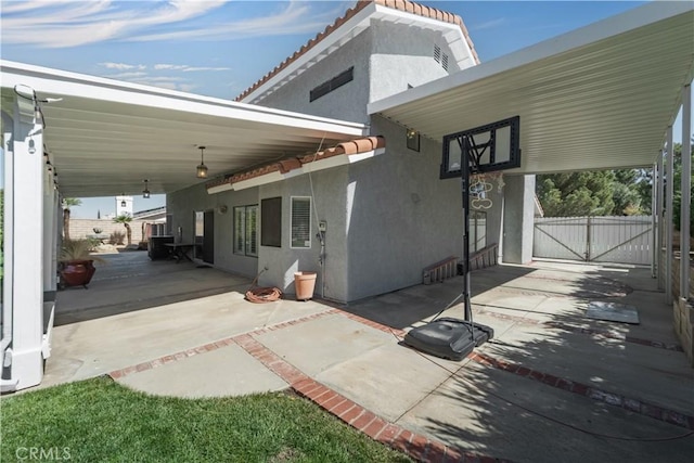 exterior space featuring stucco siding, a gate, a patio, fence, and a tiled roof