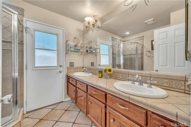 bathroom with a shower stall, double vanity, a wealth of natural light, and a sink