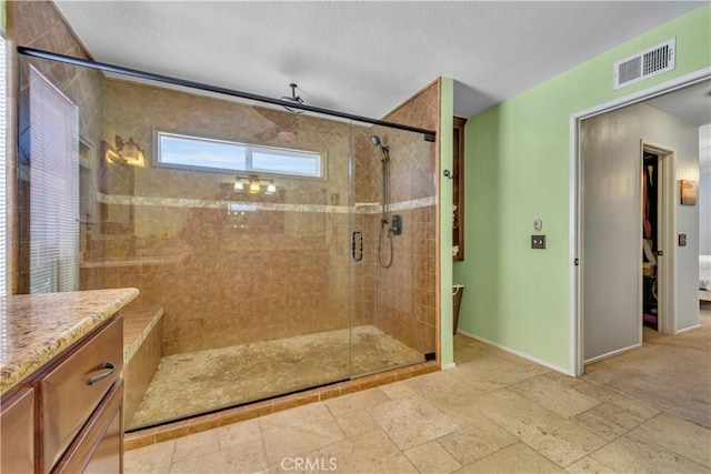 full bath featuring a shower stall, baseboards, visible vents, and a textured ceiling