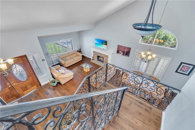 interior space featuring a fireplace, an inviting chandelier, wood finished floors, and high vaulted ceiling