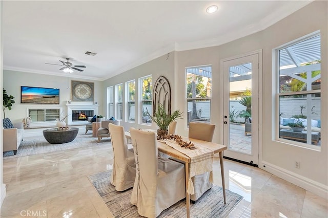 dining area with a ceiling fan, baseboards, visible vents, ornamental molding, and a glass covered fireplace