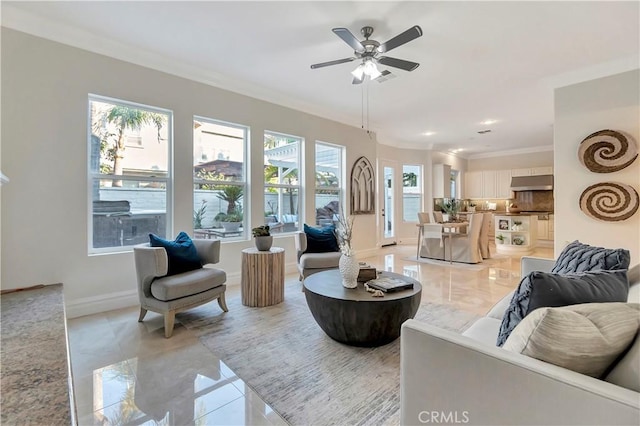 living area with a ceiling fan, baseboards, marble finish floor, and ornamental molding