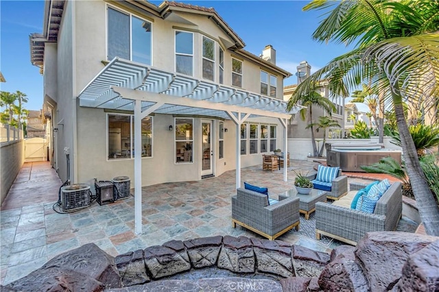 rear view of house with stucco siding, a hot tub, fence, central AC unit, and a patio area