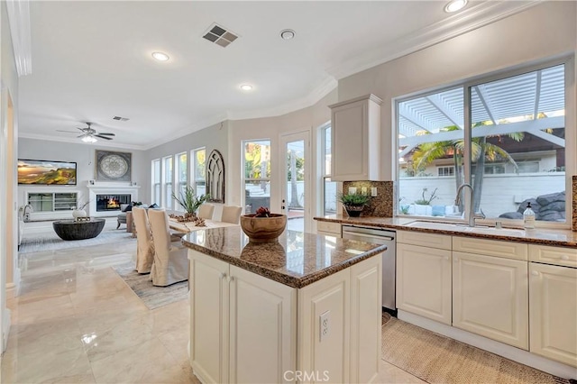 kitchen with visible vents, ornamental molding, a sink, a glass covered fireplace, and dishwasher