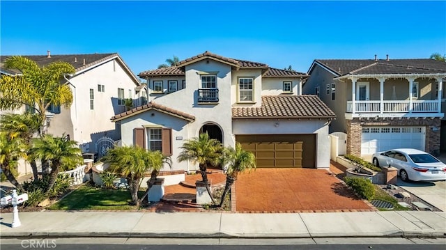 mediterranean / spanish house with stucco siding, decorative driveway, a residential view, an attached garage, and a tiled roof