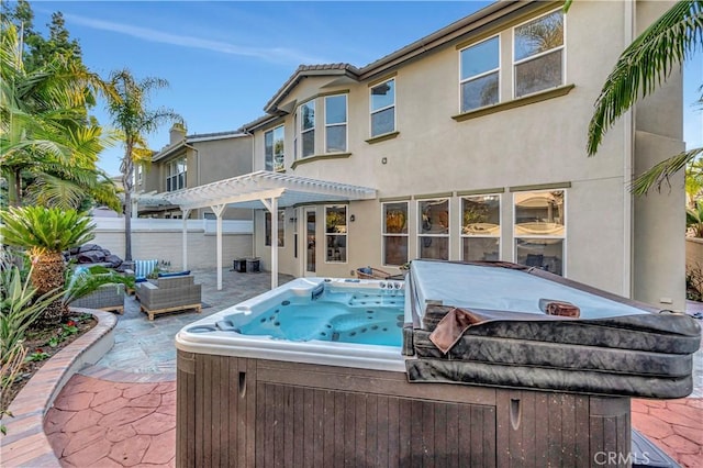 rear view of house featuring a patio, a pergola, a hot tub, and stucco siding