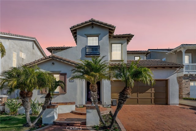 mediterranean / spanish house featuring decorative driveway, a tile roof, and stucco siding