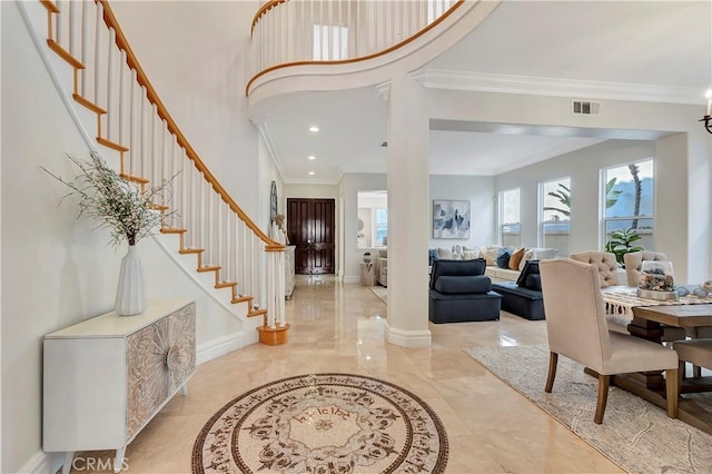 foyer featuring baseboards, visible vents, stairs, a towering ceiling, and crown molding