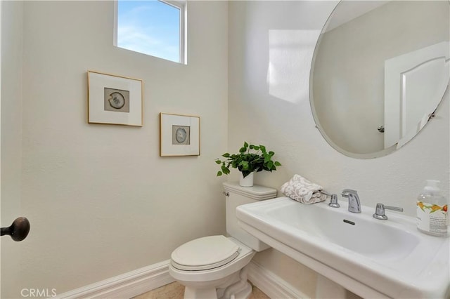 bathroom featuring toilet, baseboards, and a sink