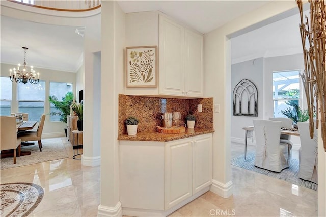 bar featuring decorative backsplash, a notable chandelier, marble finish floor, and ornamental molding