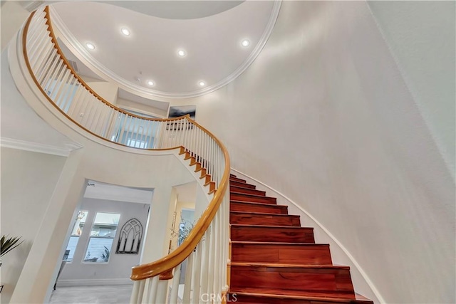 stairway with crown molding, a high ceiling, recessed lighting, and baseboards