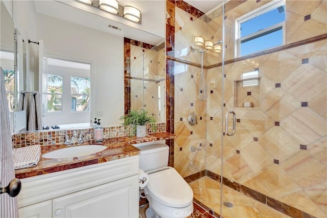 bathroom with decorative backsplash, toilet, plenty of natural light, and visible vents