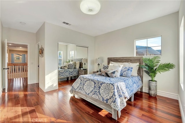 bedroom with wood finished floors, visible vents, a closet, and baseboards