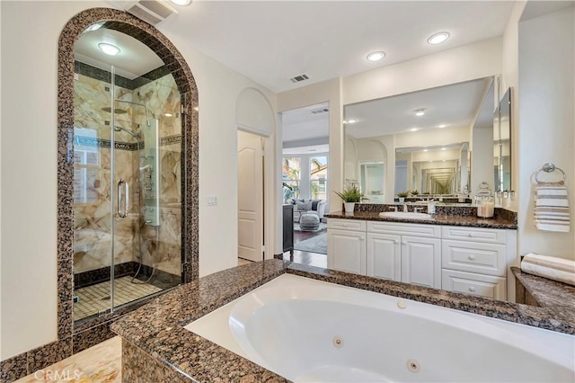 bathroom featuring vanity, a tub with jets, visible vents, and a stall shower