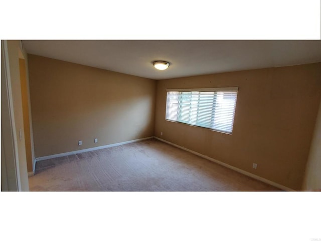 unfurnished room with carpet flooring and baseboards