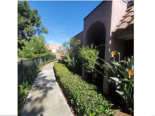 view of side of home with stucco siding and fence